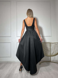 Black evening gown styled against white panelled walls