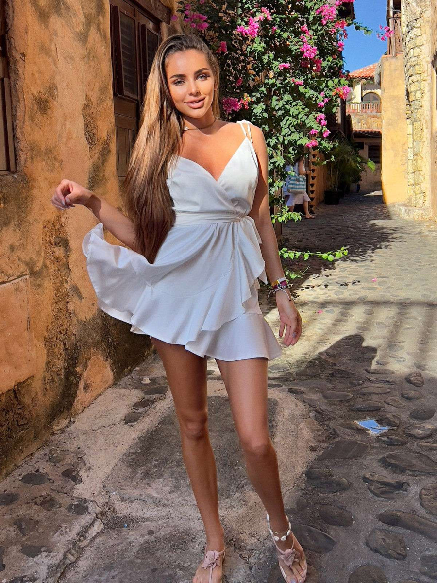 Woman in a white dress standing on a stone street with flowers and buildings in the background
